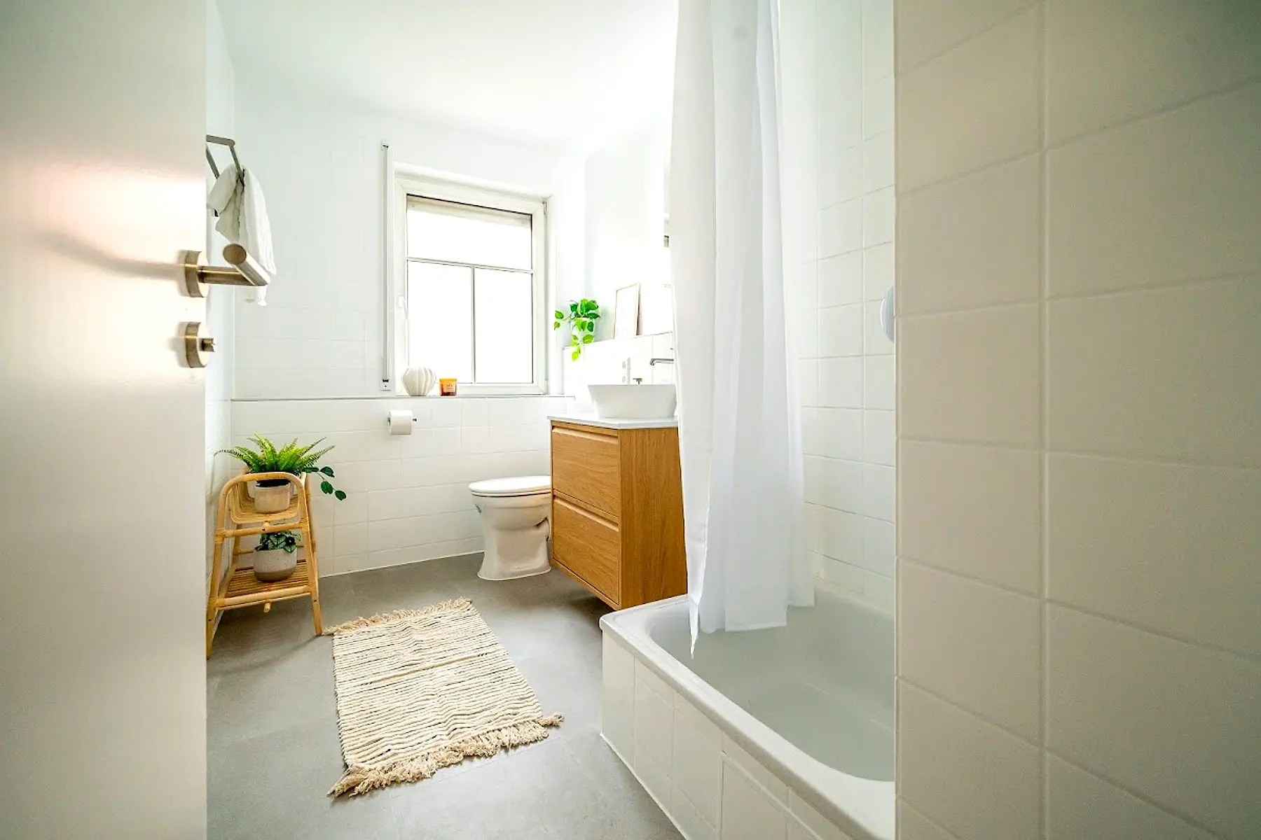 Helles Bad mit Wanne, Holzunterschrank und Fenster